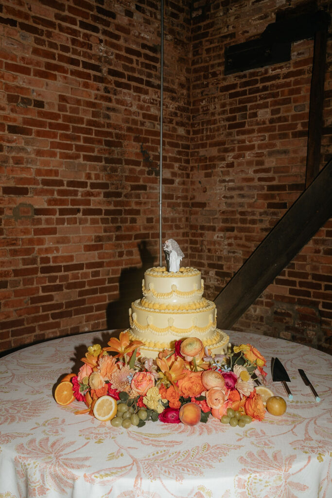Empire Mills wedding cake surrounded by flowers and citrus fruits.
